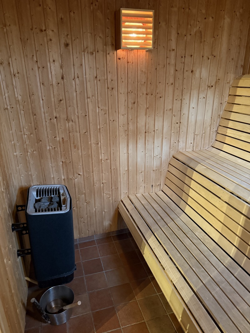 Spaavdelning med två duschar, en toa, bastu, vinkyl samt fotöljer